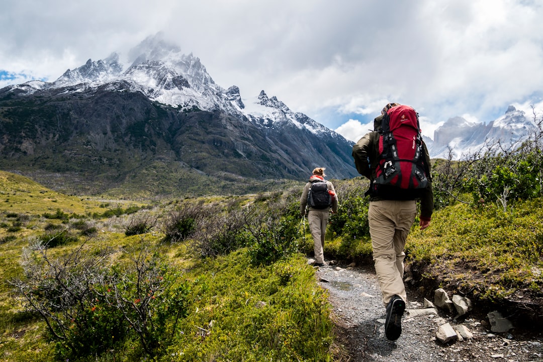A collection of essential hiking gear laid out on a wooden surface, including a backpack, water bottle, map, and trekking poles.