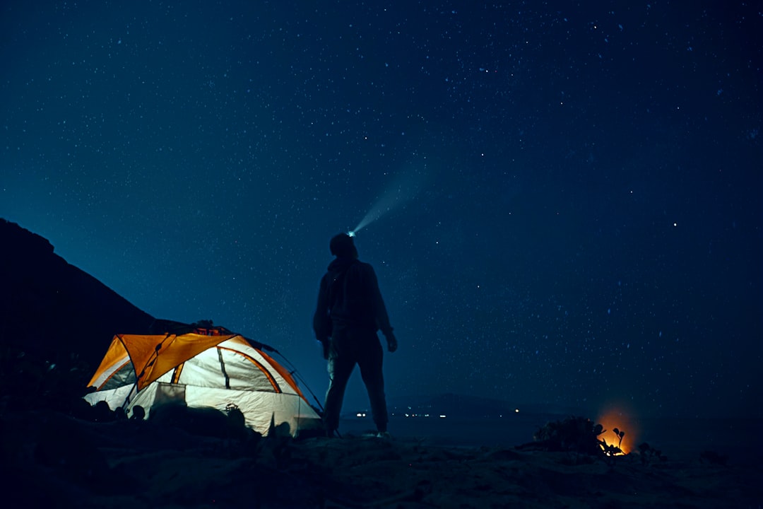 A backpack with essential camping and hiking gear laid out on a grassy area, showcasing a minimalist packing approach.